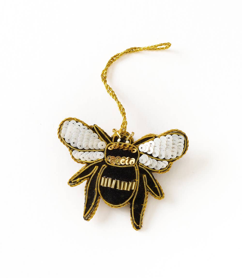 Decorative bee ornament with gold and black details on a white background