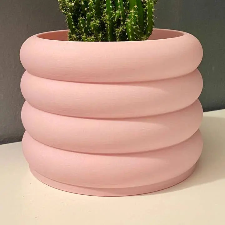 Pink ribbed planter with a cactus on a neutral background