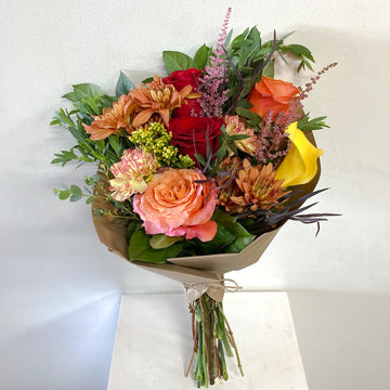 Bouquet of colorful flowers wrapped in paper with greenery on a white background