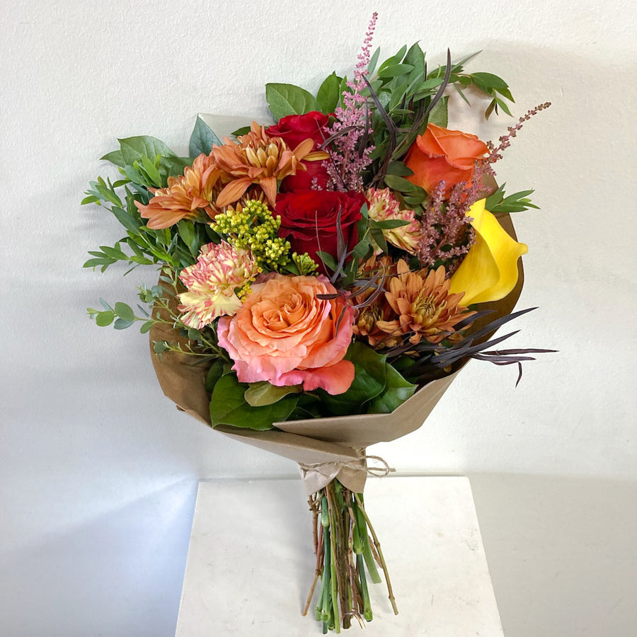 Bouquet of colorful flowers wrapped in paper with greenery on a white background