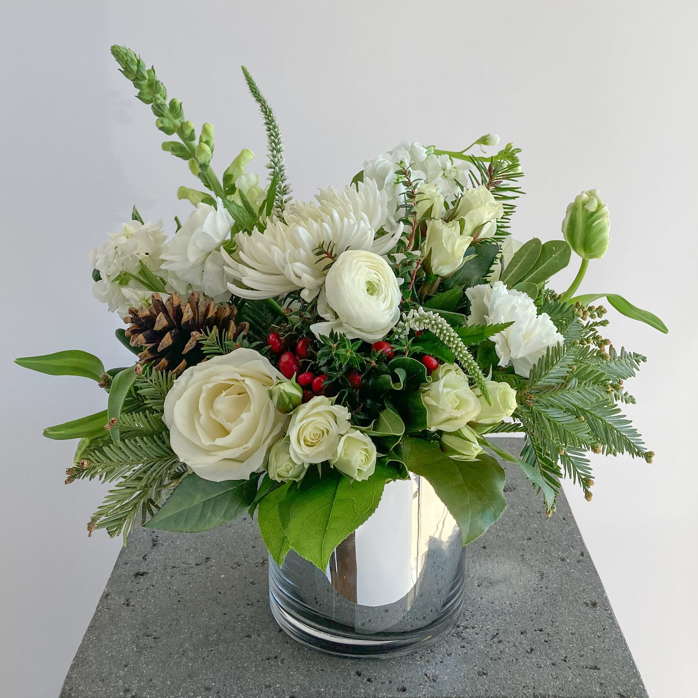 Floral arrangement with white flowers and Christmas greenery in a vase