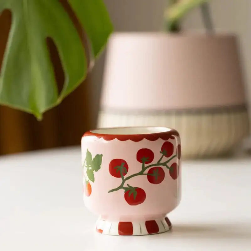Small ceramic cup with tomato design on a white surface