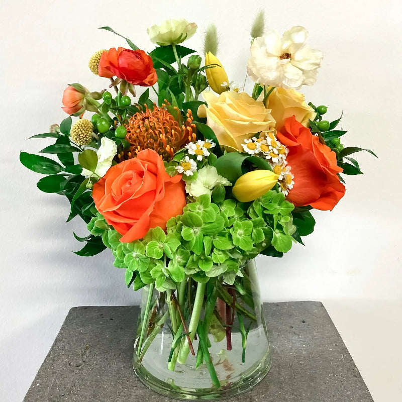 Bouquet of flowers in a glass vase on a gray surface with a white background
