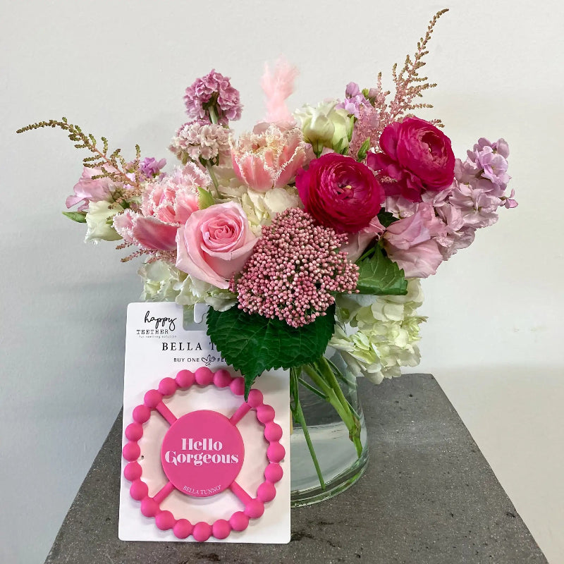 Bouquet of pink and white flowers with a 'Hello Gorgeous' card on a gray surface.
