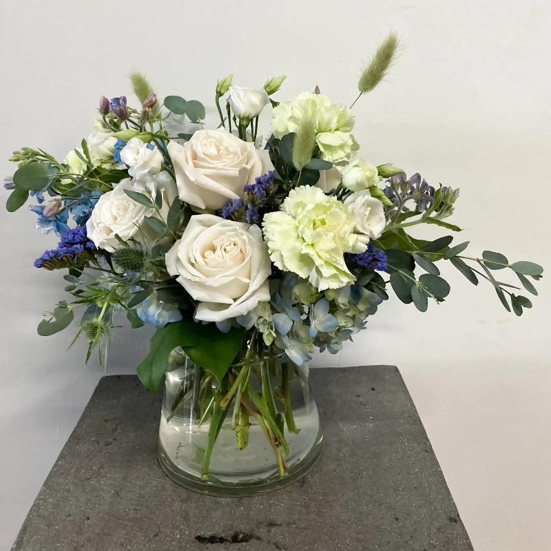 Bouquet of flowers in a clear vase on a gray surface with a light gray background
