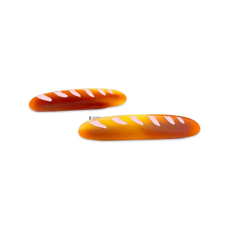 Two orange bread-shaped hair clips on a white background