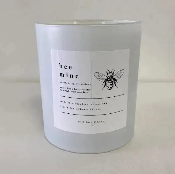 White candle with a label featuring a bee illustration on a white background