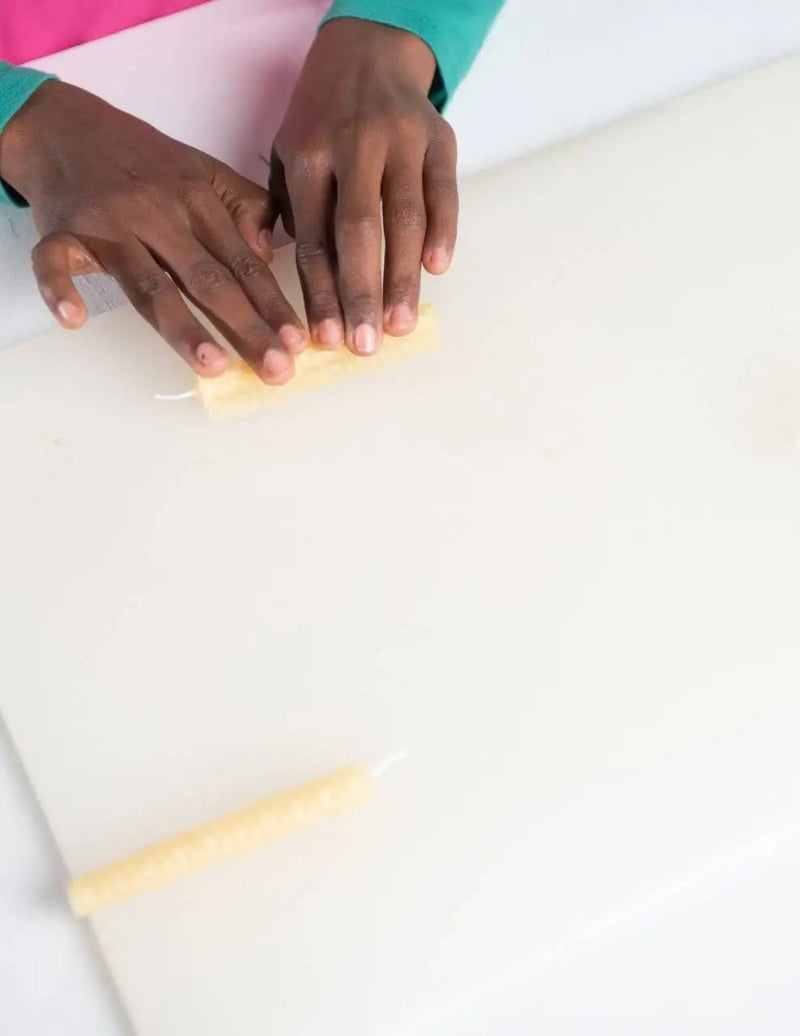 Close-up of hands using a yellow sponge on a white surface