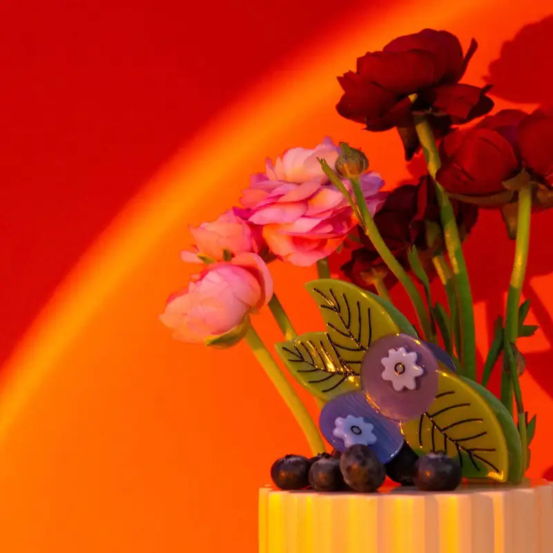 Artificial flowers and berries with a blueberry hair claw on a stand with a vibrant red background