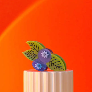 Colorful floral earrings on a wooden block with an orange background
