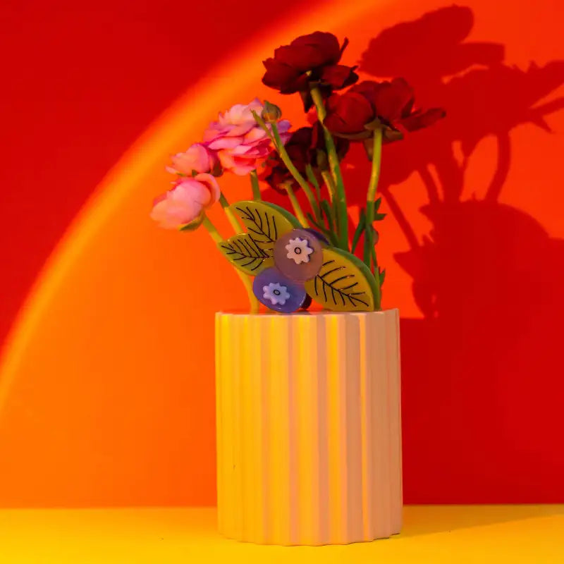 Floral arrangement in a striped vase against a red and orange gradient background