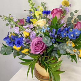 Bouquet of colorful flowers including roses and hydrangeas on a white surface.