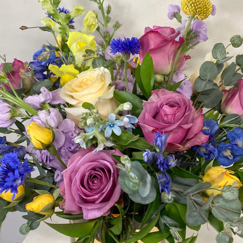 Bouquet of colorful flowers including roses and hydrangeas on a light background