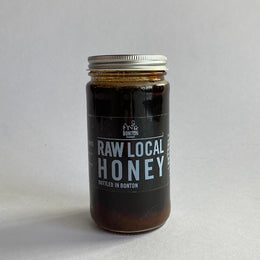 Jar of raw local honey on a light gray background