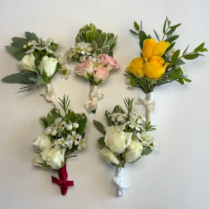 Five floral boutonnieres arranged in a decorative pattern on a white background