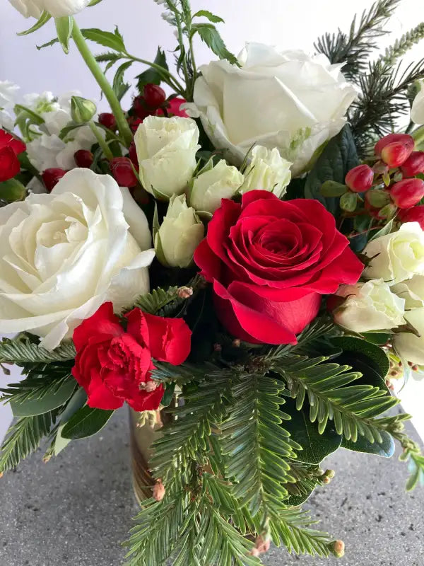 Bouquet of red and white roses with greenery on a light background