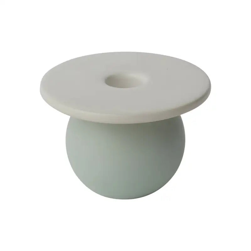 White ceramic candlestick on a light green base against a white background