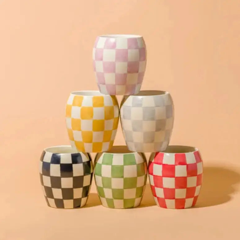 Stack of checkered ceramic cups on a peach background