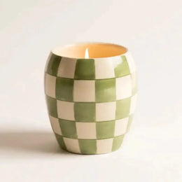 Checkered ceramic candle holder with a lit candle on a white background