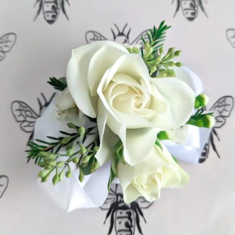 White flower corsage with greenery on a light background