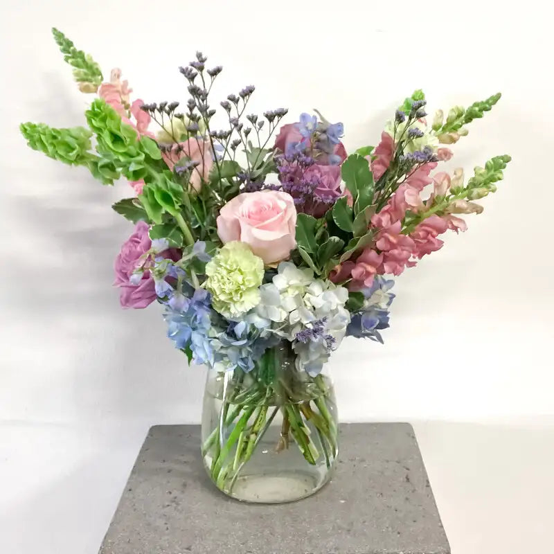 Bouquet of colorful flowers in a clear vase on a white background