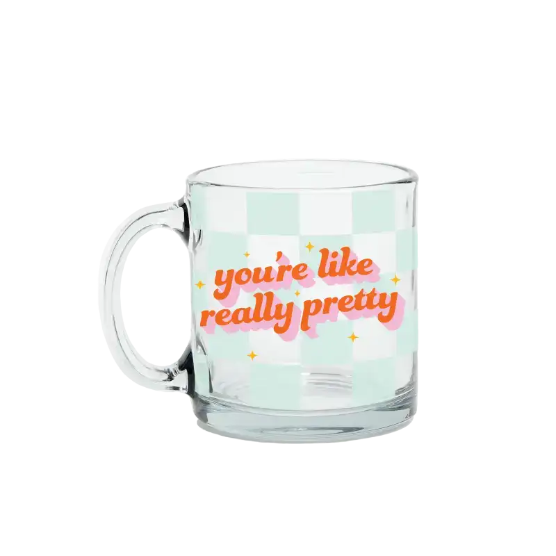 Clear glass mug with colorful text on a light green background