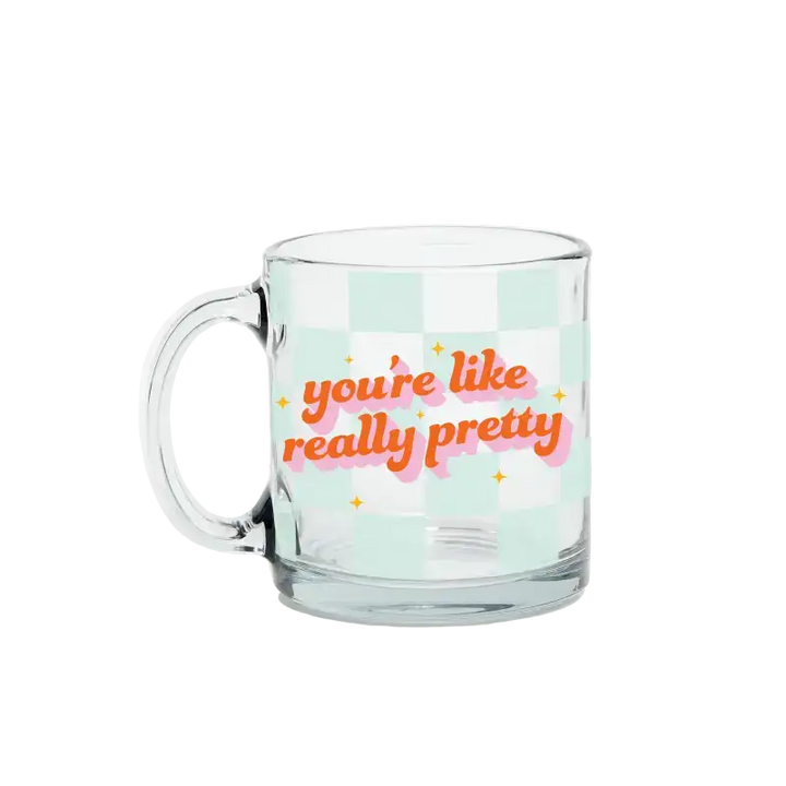 Clear glass mug with colorful text on a light green background