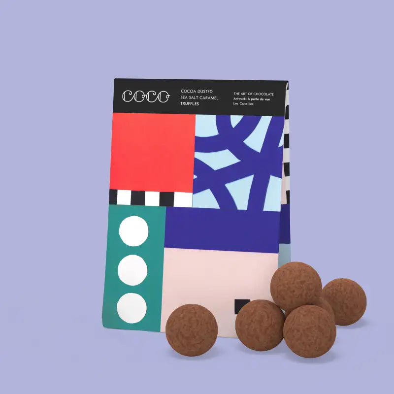 Cocoa-dusted truffles in front of a colorful packaging on a light purple background