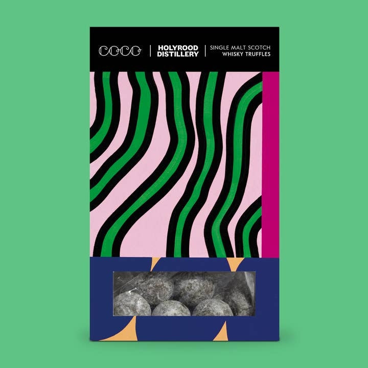 A rectangular product package for Holyrood Distillery Single Malt Scotch Whisky Truffles, shown against a solid green background. The packaging features a black top band with white text, a pink and green wavy zebra-like pattern, a vertical magenta stripe, and a dark blue lower section with a clear window revealing grey truffles inside.