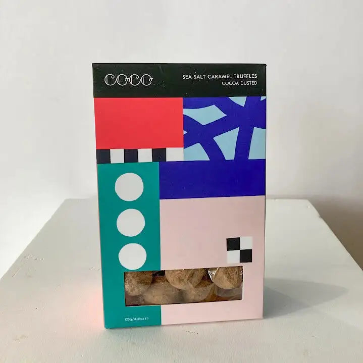 Colorful box of sea salt caramel truffles with geometric design on a white surface.