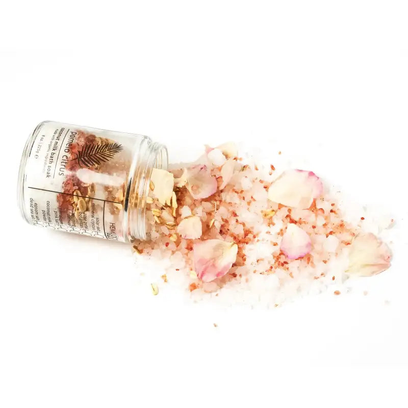 Open jar of bath salts with pink and white flowers on a white background