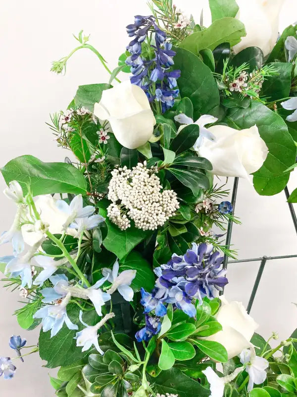 Bouquet of flowers with green leaves, white roses, and blue hydrangeas on a white background