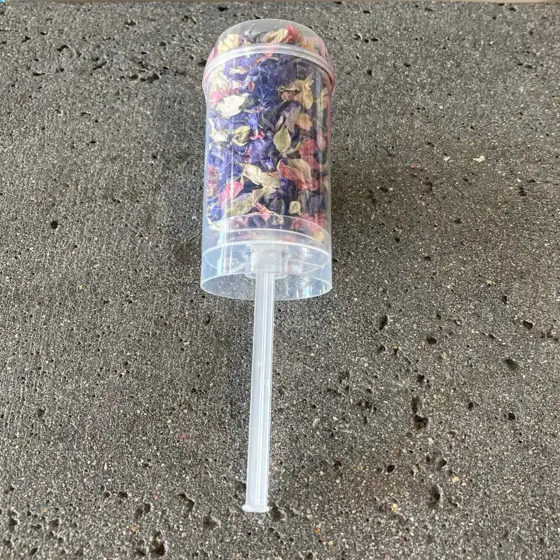 Clear plastic cup with colorful contents on a gray concrete surface