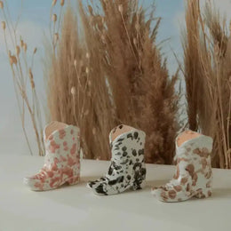 Three decorative boots with floral and polka dot patterns on a neutral background