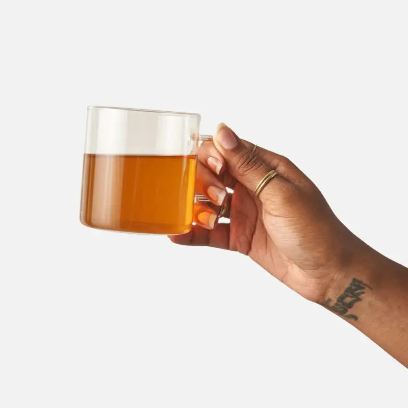 Hand holding a glass mug with a drink on a white background