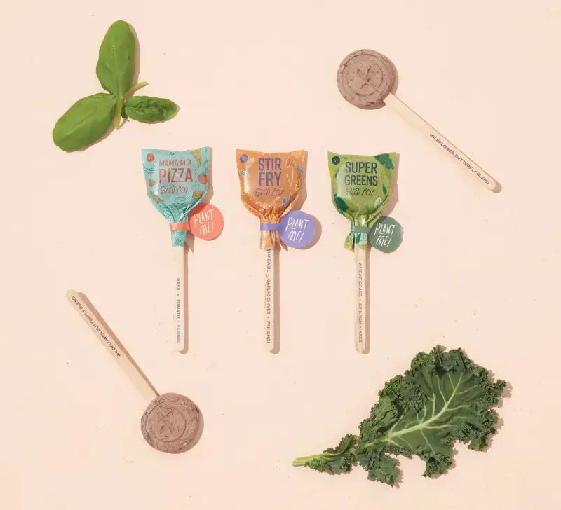Four lollipops with packaging labeled 'Pizza', 'Stir Fry', 'Super Greens', and 'Plant Free' on a beige background.