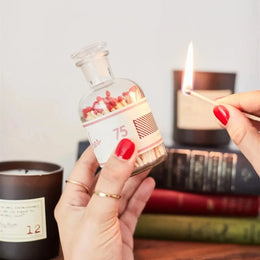 Person lighting a match from a bottle filled with matches and decorative items.