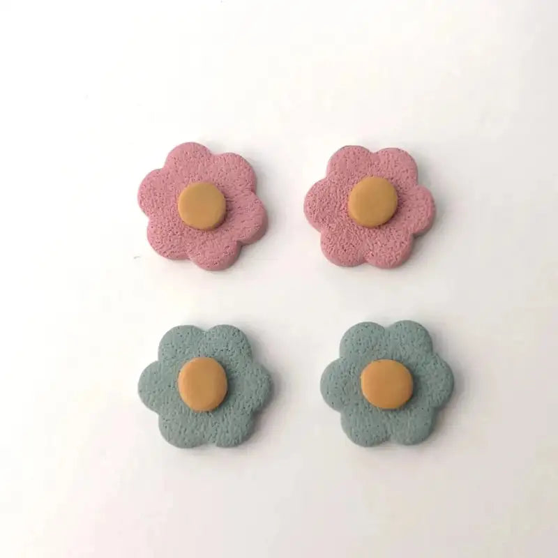 Four flower-shaped earrings with pink and green petals and a brown center on a white background.