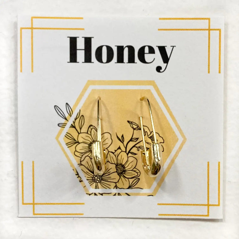 Gold earrings on a card with floral design and 'Honey' text