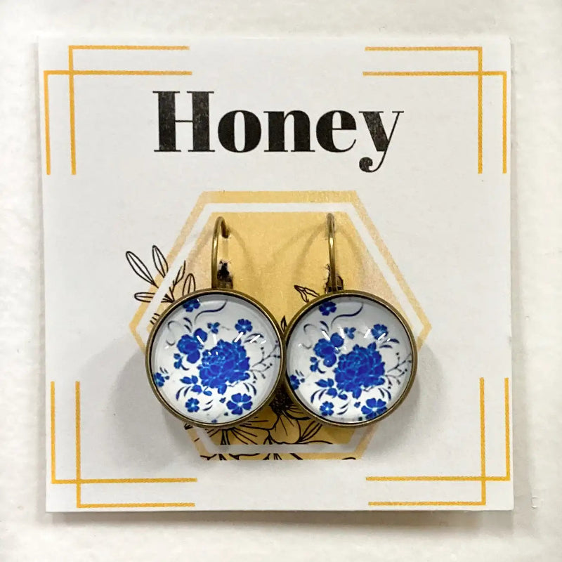 Earrings with blue floral design on a card with 'Honey' text