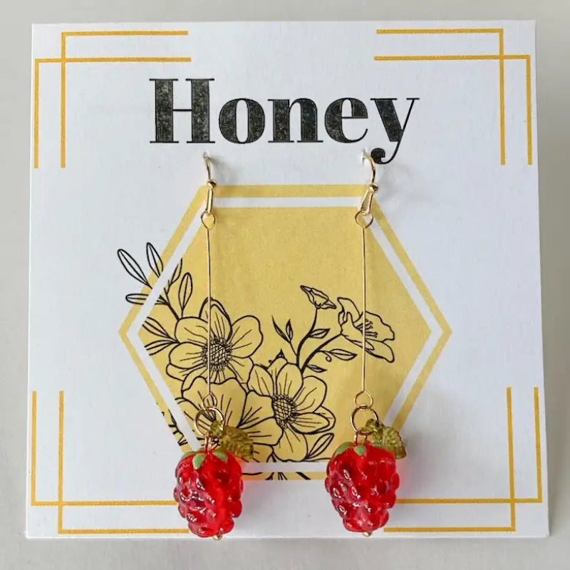 Strawberry-themed earrings on a decorative card with floral design and 'Honey' text.