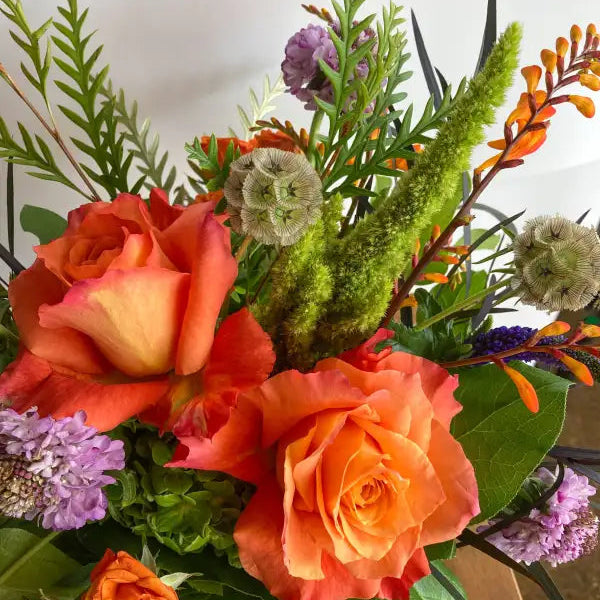 Bouquet of orange roses and greenery with a neutral background