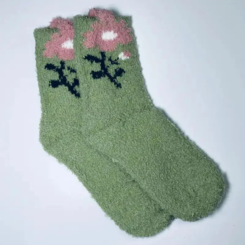 Green socks with pink flowers and black leaves on a white background