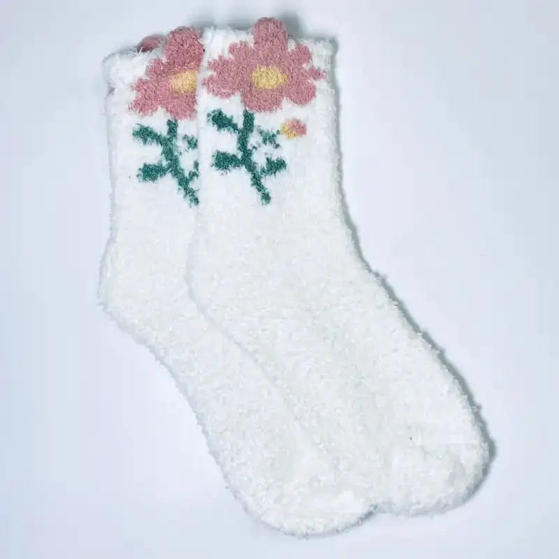 White fuzzy sock with pink flowers and green snowflakes on a light gray background
