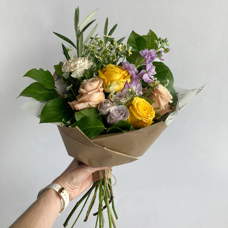 pastel flowers and greenery wrapped in brown paper