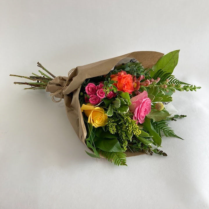 Bouquet of flowers wrapped in brown paper on a white background