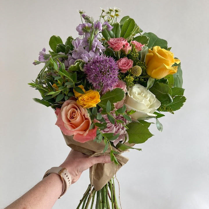 Bouquet of colorful flowers held by a person against a plain background