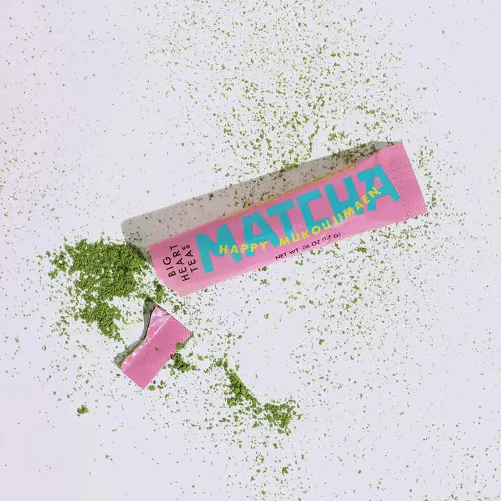 Matcha green tea powder packaging with green powder spilling out on a white background