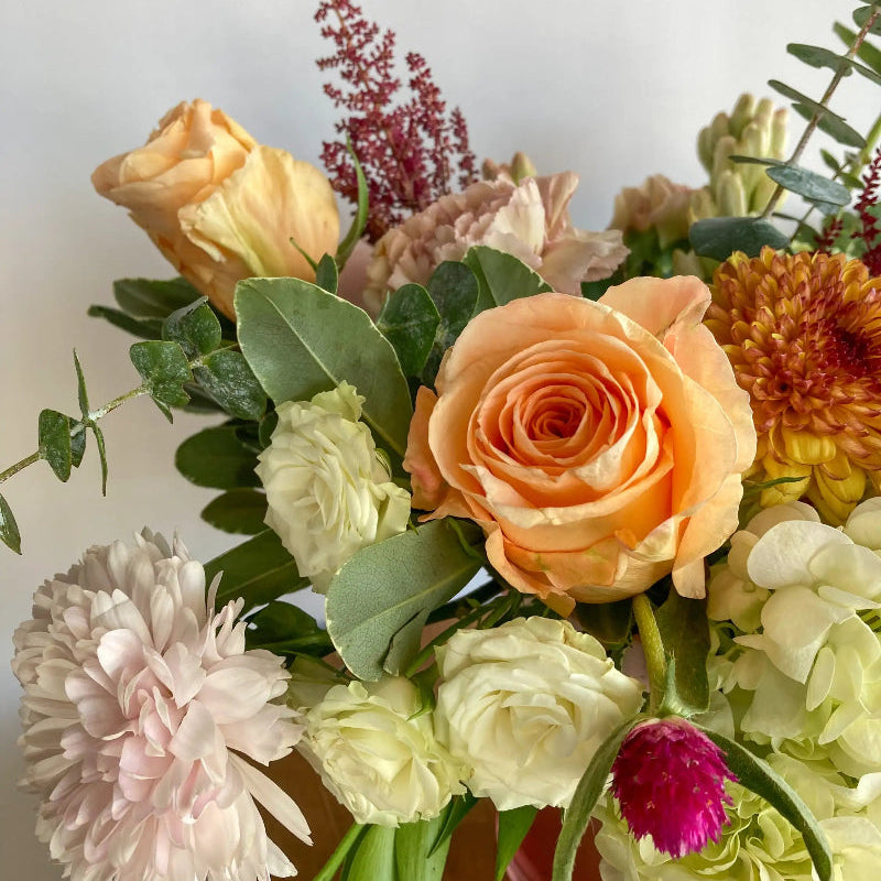 Bouquet of colorful flowers including roses and dahlias on a light background