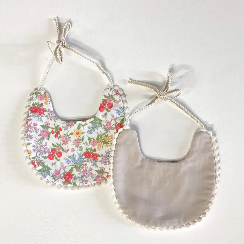 Two baby bibs, one with a floral pattern and the other plain gray, on a light background.